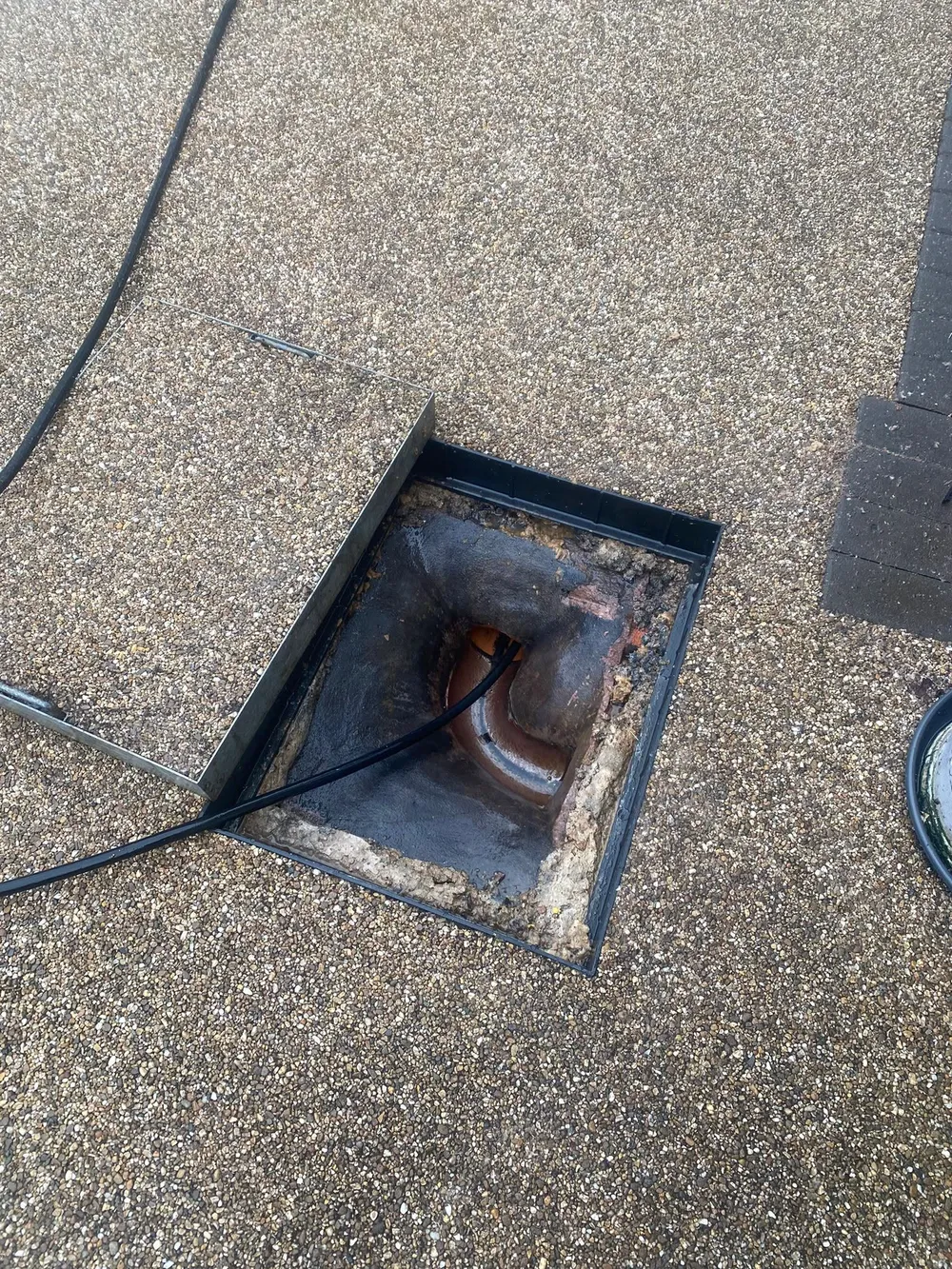 Accessible drain chamber showing the channel and drainage hose after clearing